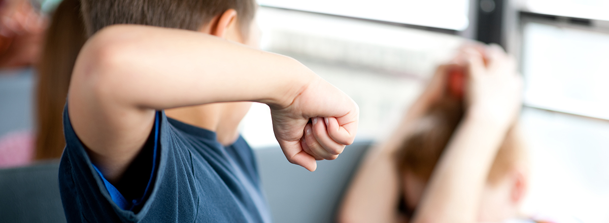 A bully getting ready to hit a boy on a school bus. Very shallow depth of field.